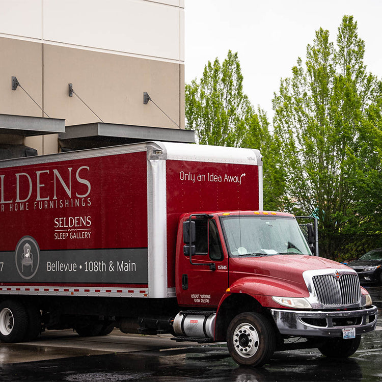 A red Seldens delivery truck backed up to a warehouse door.