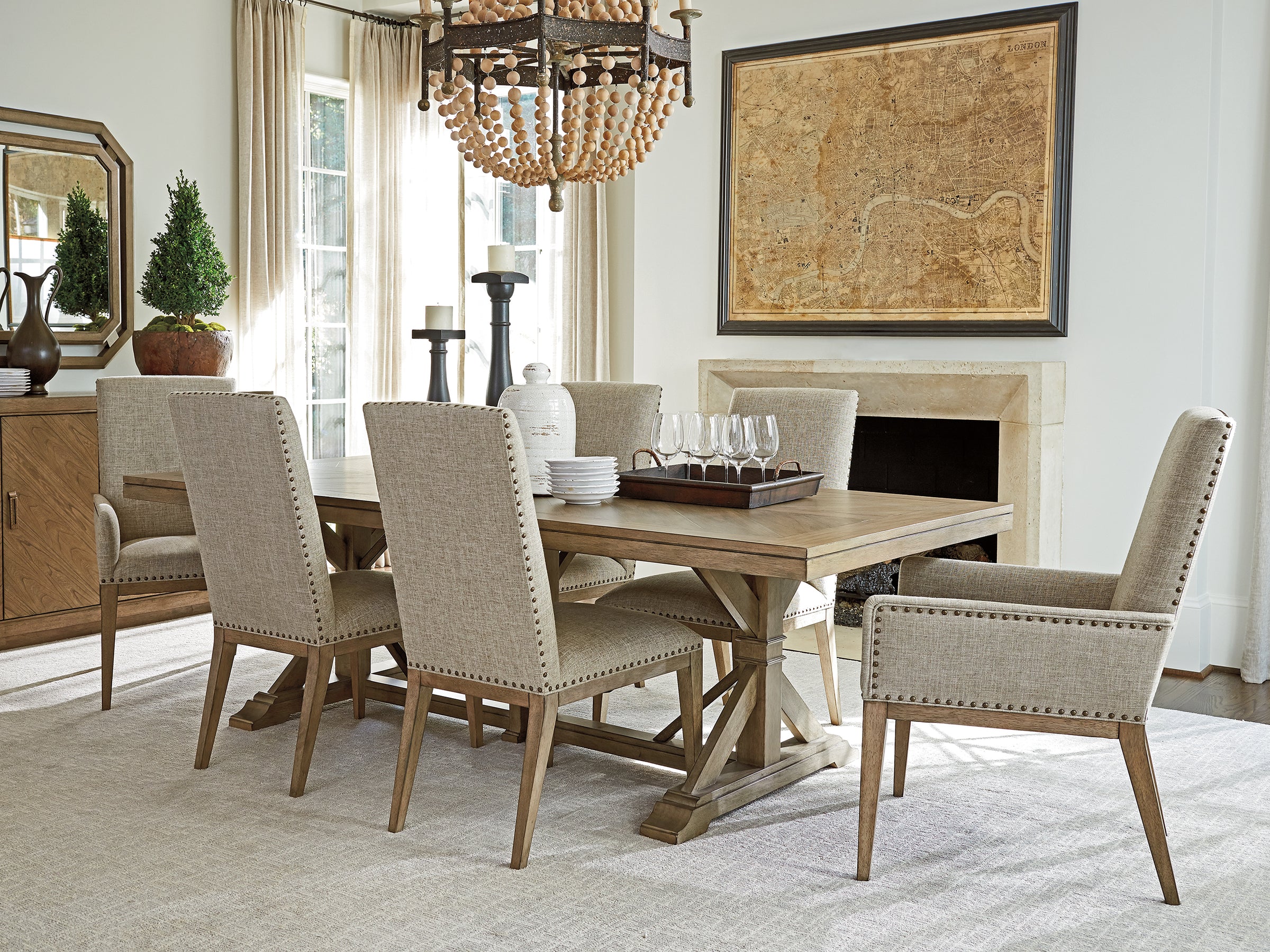 Dining room scene from Tommy Bahama Home's Cypress Point collection featuring a tan wood dining table surrounded by matching fabric and wood dining chairs.
