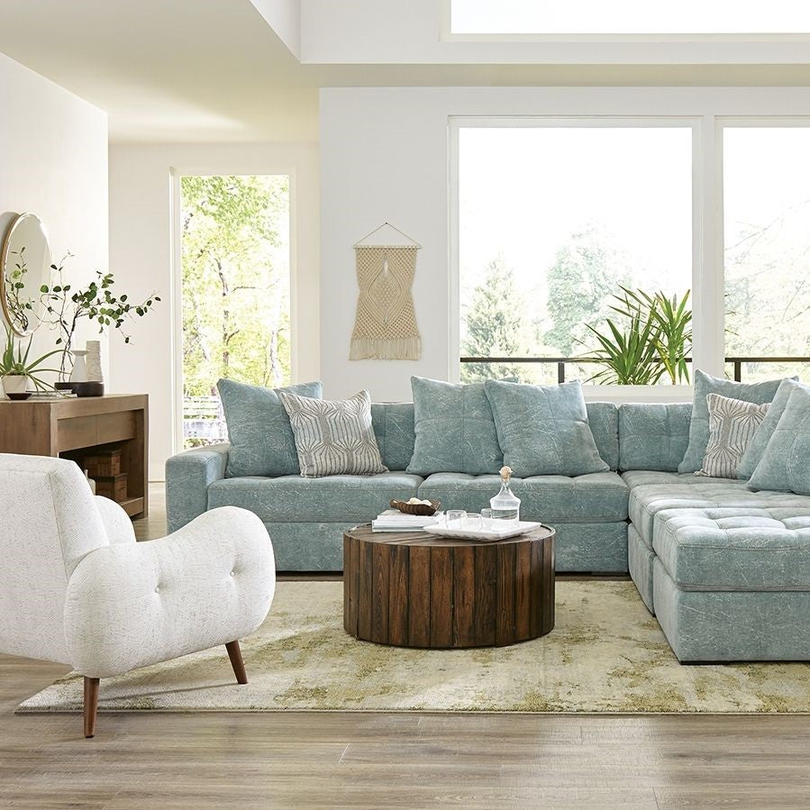 large, light blue sectional sofa and white arm chair in a casual living room setting.