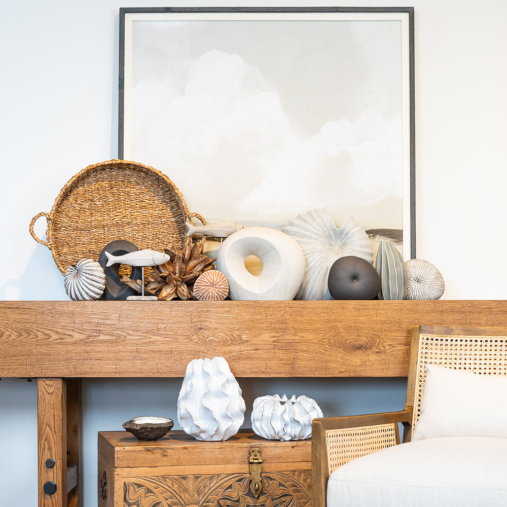Home decor pieces on a console table in front of a landscape painting