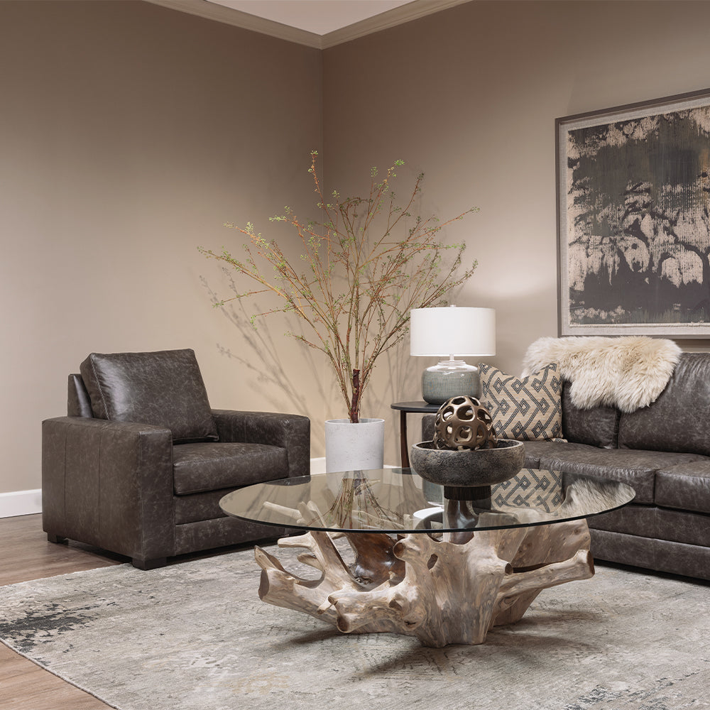 dark grey leather chair in living room scene with a rustic wood and glass coffee table in front.