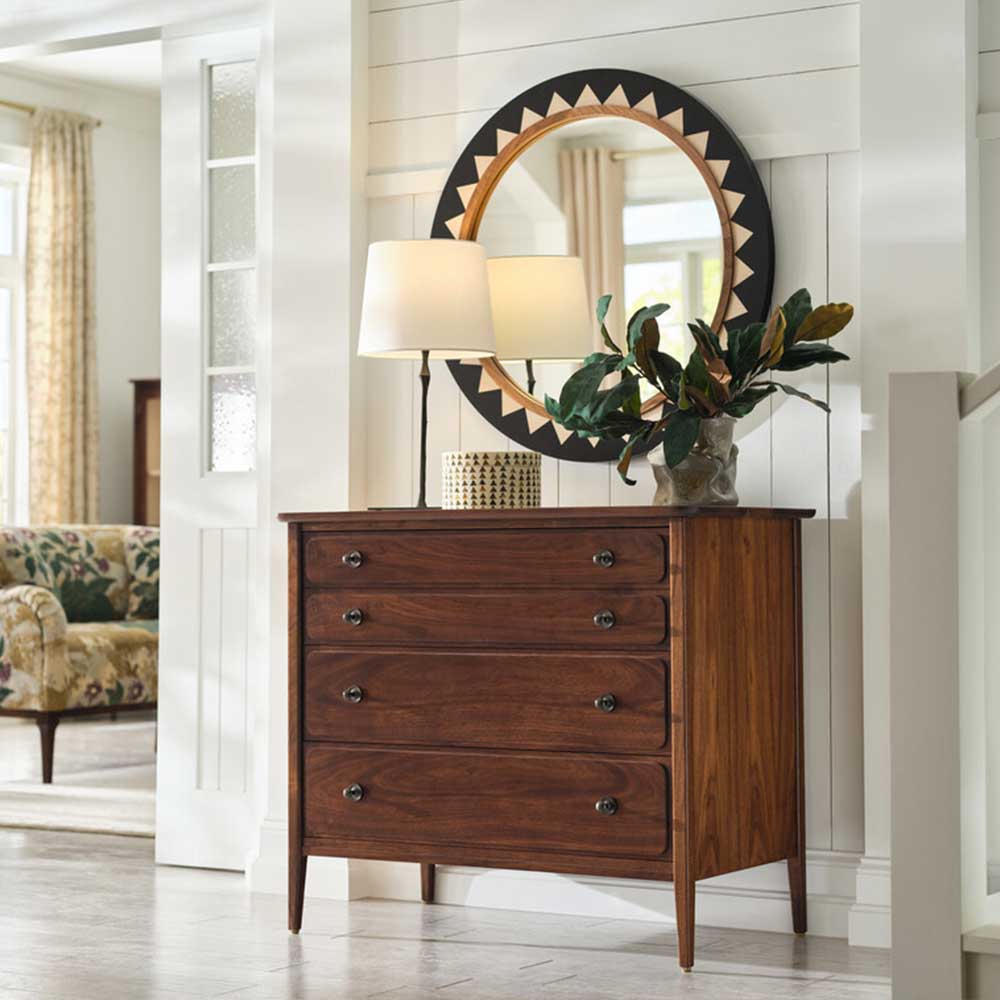 metal sunburst shaped mirror hanging on wall above cabinet with accessories