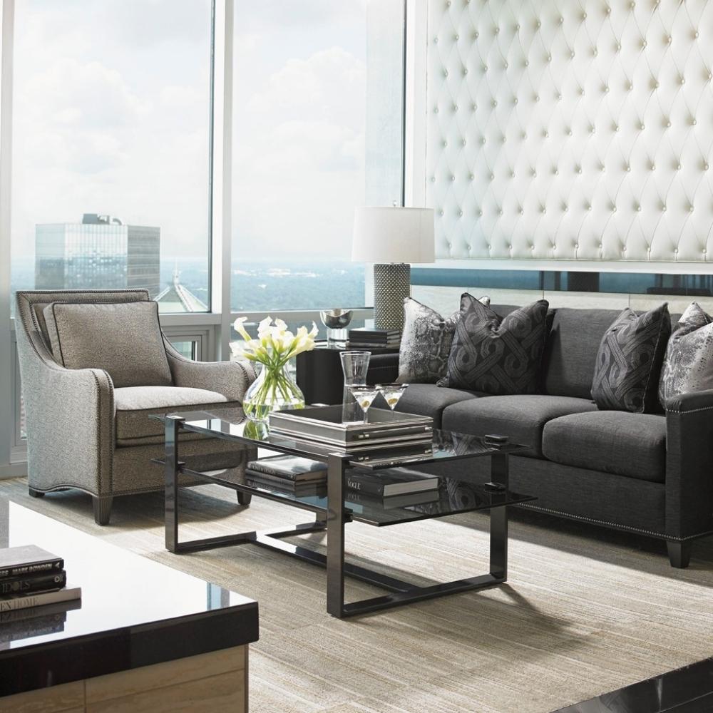 modern living room scene with dark fabric sofa, grey fabric arm chair, and metal with glass coffee table.