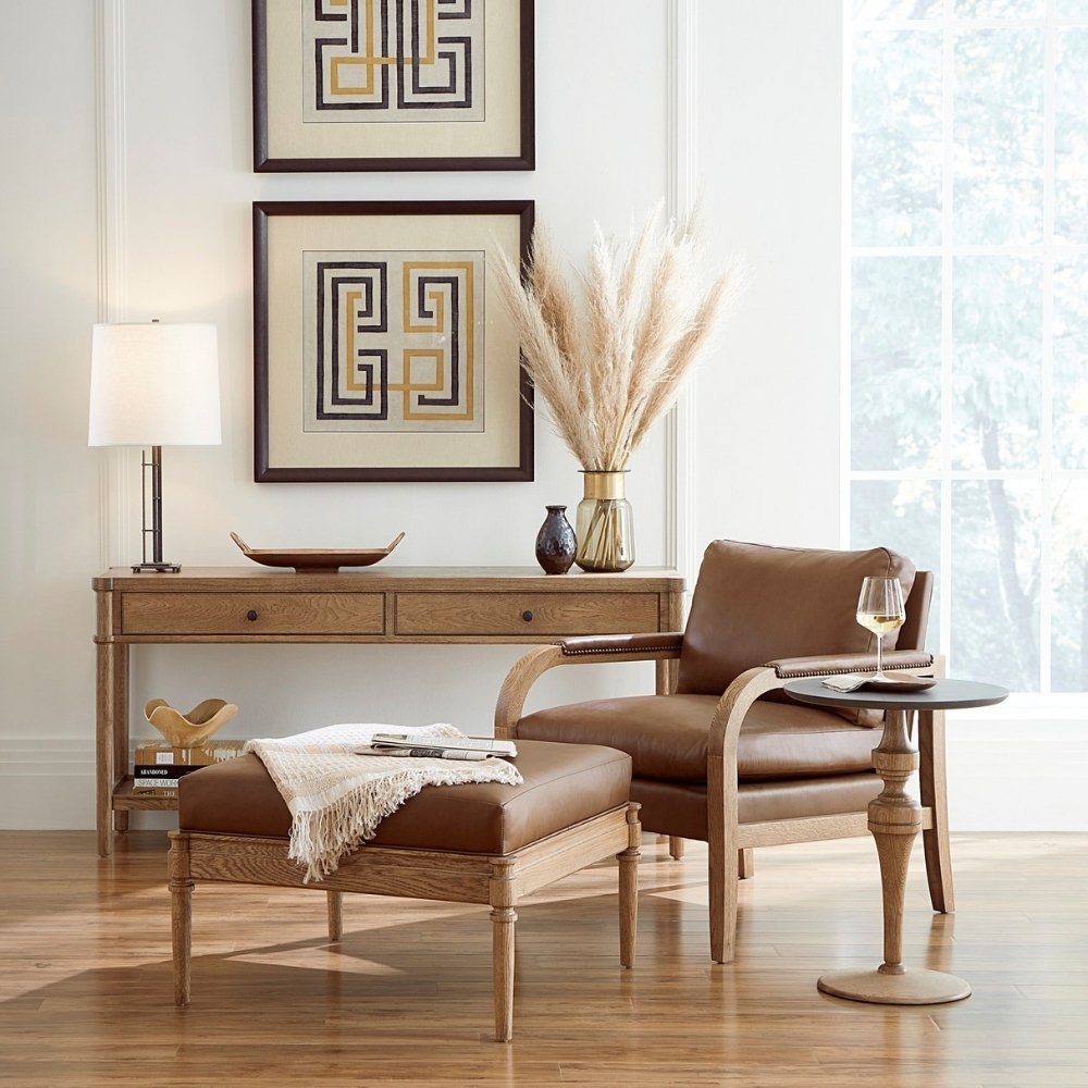 stickley st lawrence sitting area scene with brown leather and wood chair with ottoman and side table in front of console table