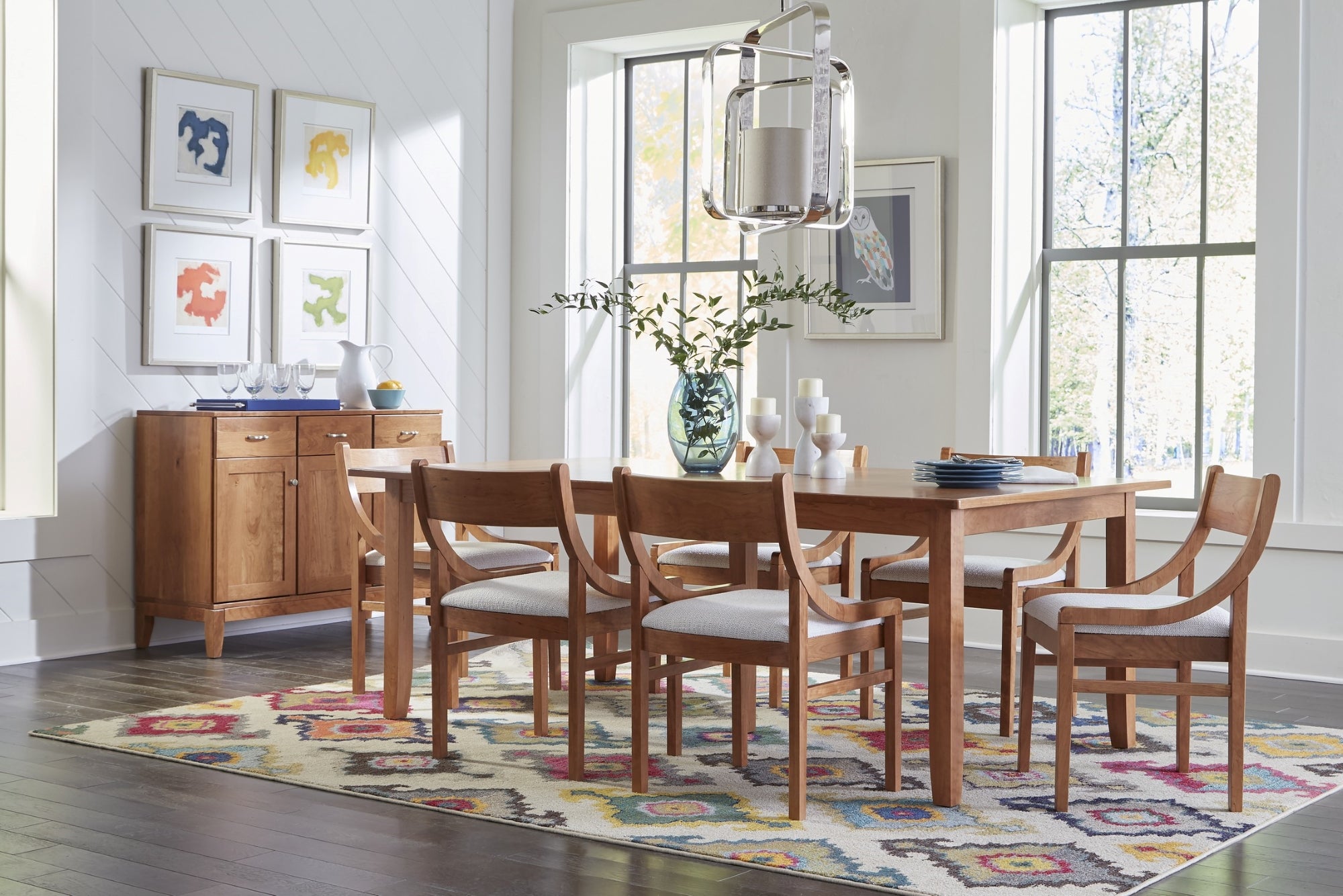 Large medium wood dining table surrounded by matching dining chairs and flanked by a matching medium wood credenza