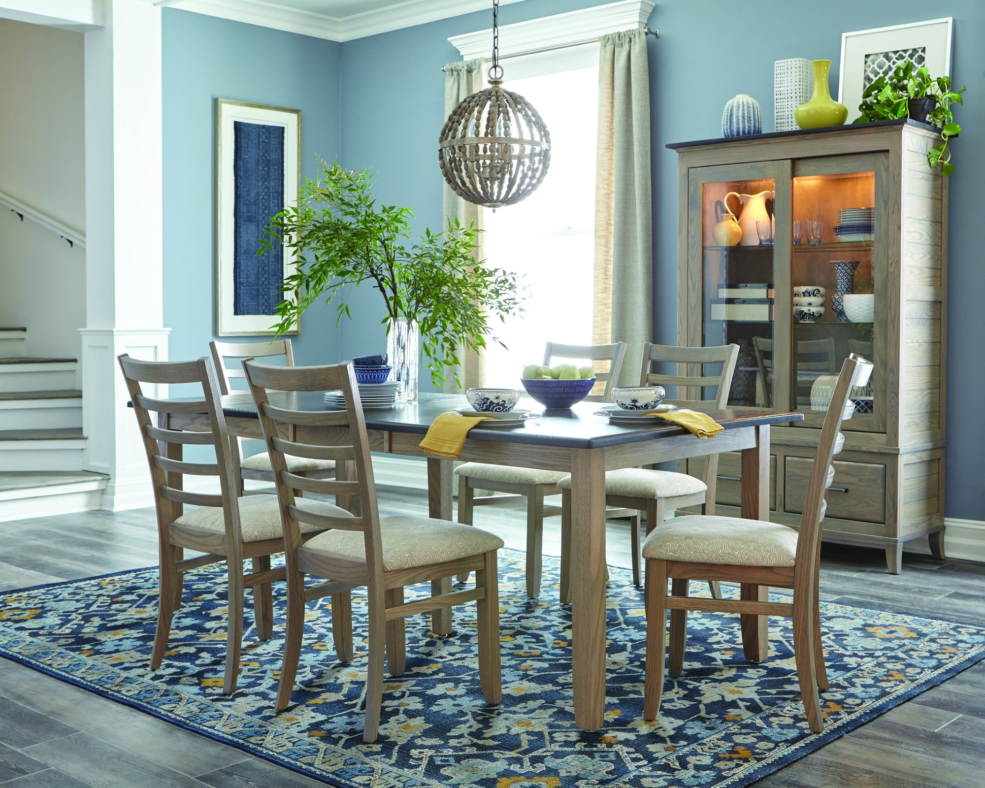 Two-tone wood dining rectangle dining table surrounded by six wood dining chairs with fabric seats.