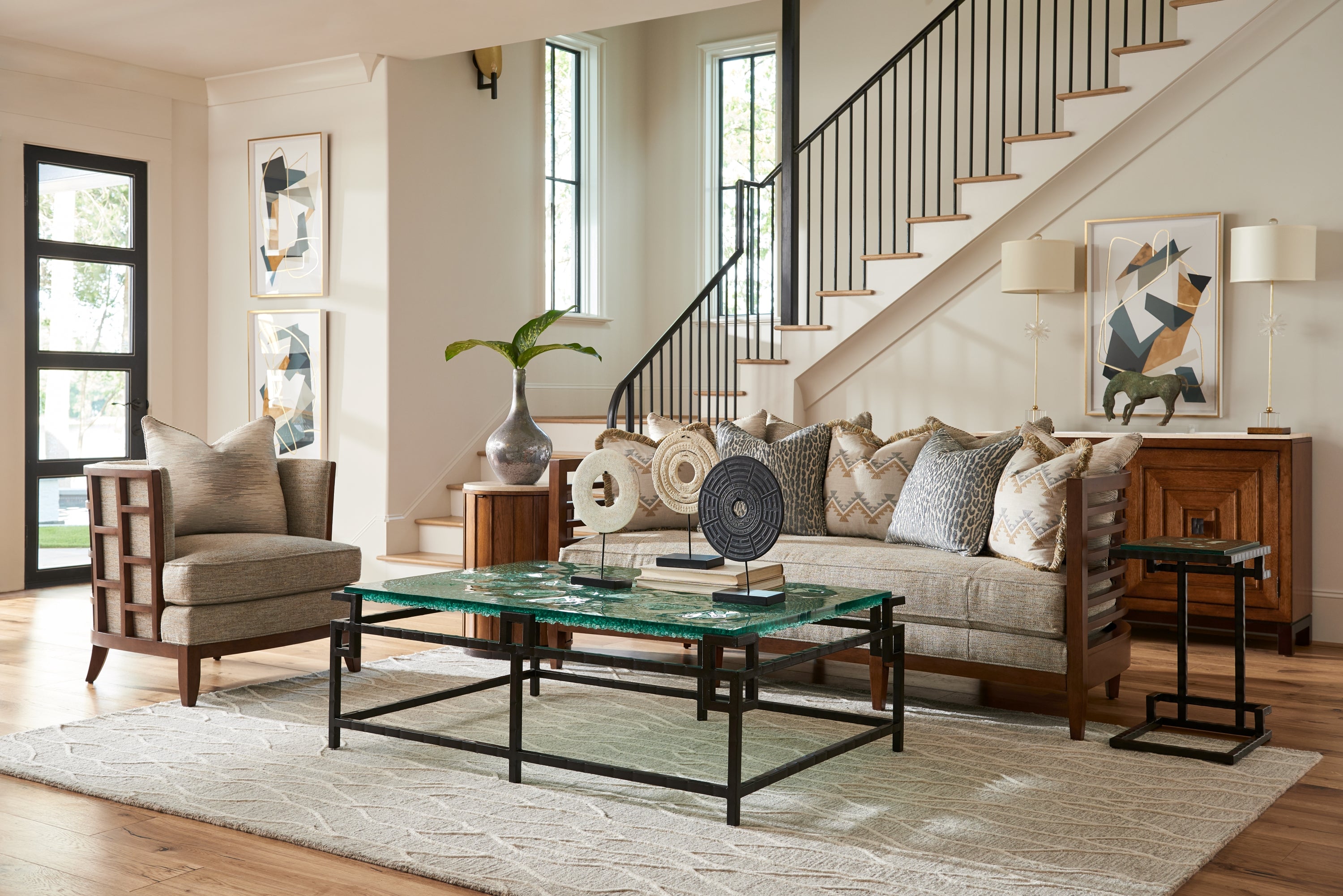 Living room scene from Tommy Bahama Home featuring a wood and fabric sofa and arm chair with a metal and glass cocktail table.