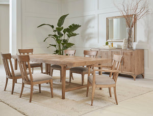 A light wood, rectangular dining table is surrounded by matching dining chairs with beige fabric seats. A matching light wood buffet sits against the side wall under a large square mirror.