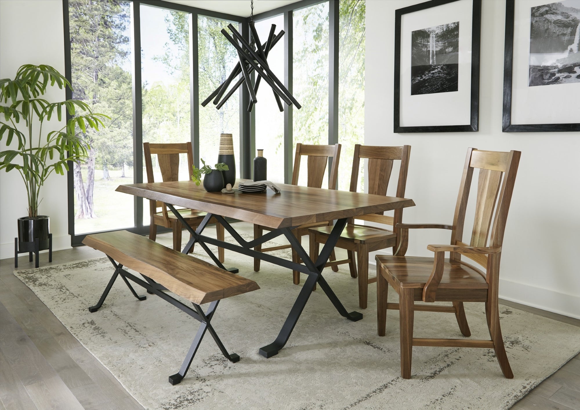 Live edge wood dining table with black metal base and matching bench with four wood dining chairs