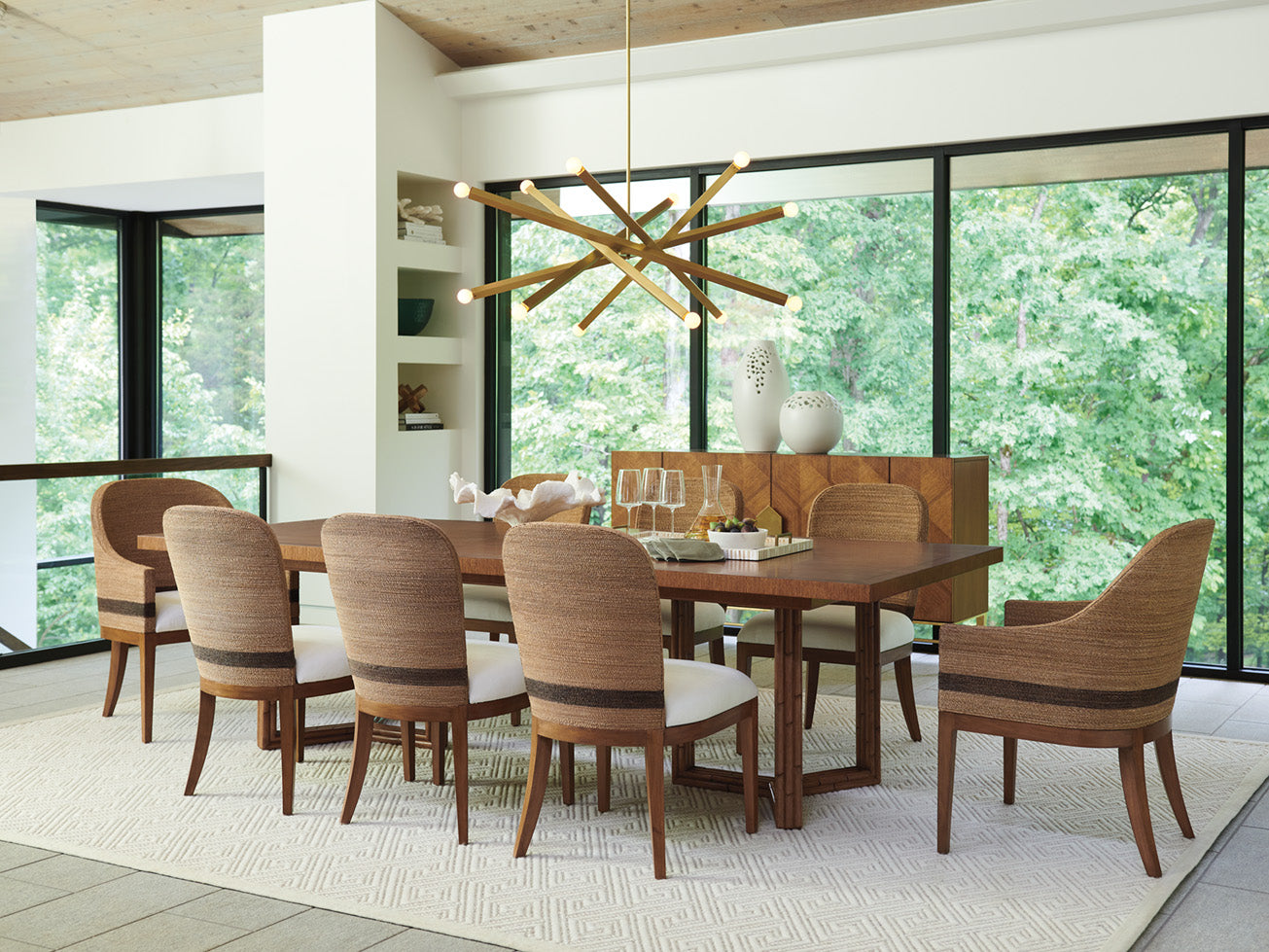 Dining room scene from Tommy Bahama Home's Palm Desert collection featuring a large medium wood dining table surrounded by matching rattan dining chairs.