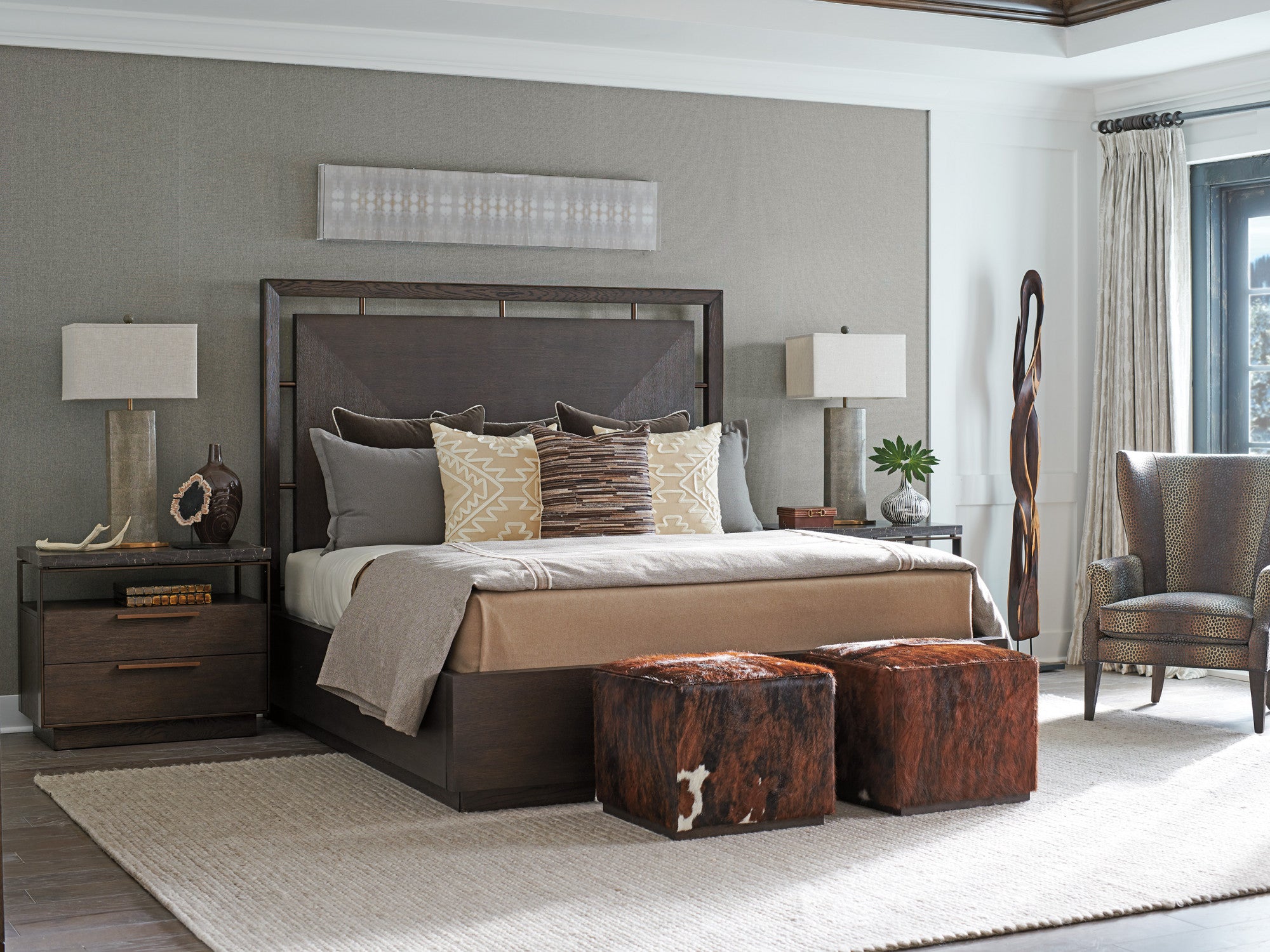 Bedroom scene from Barclay Butera's Park City collection featuring a dark wood bed with matching nightstands and hide-covered ottomans.