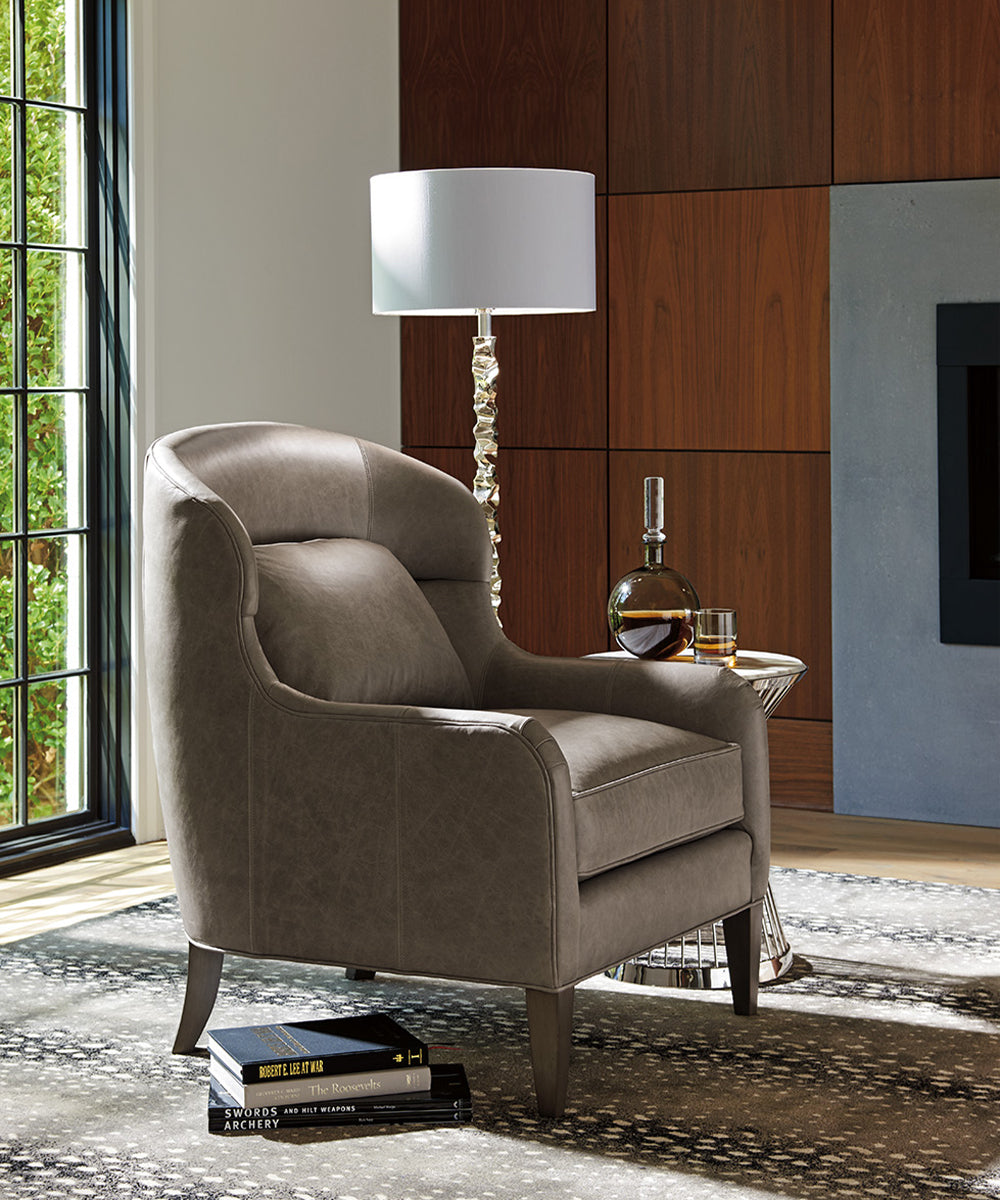 A taupe leather chair next to a lamp and side table.