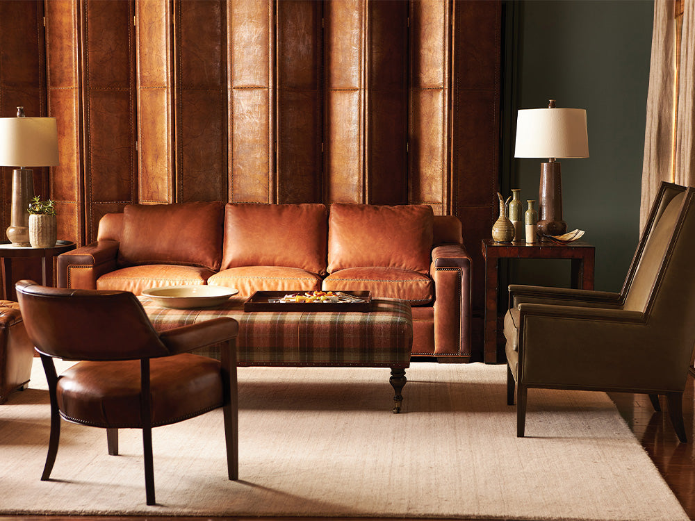 A traditional and rustic living room scene from Hancock and Moore featuring a brown leather sofa and an upholstered cocktail ottoman.