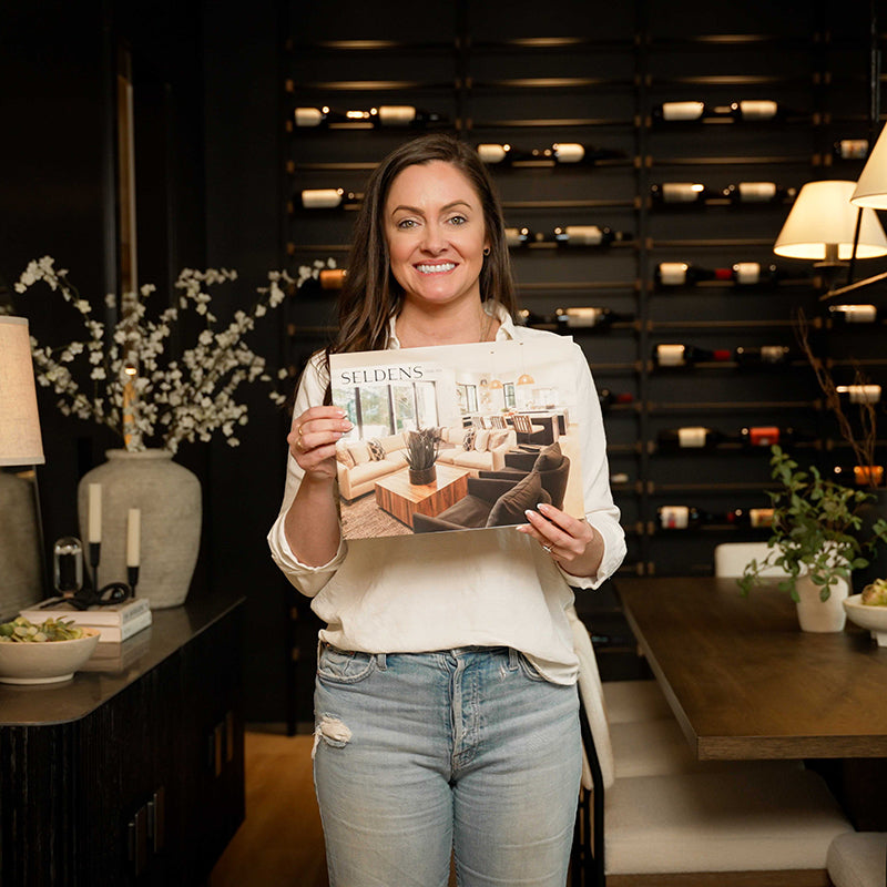 Molly Mesnick standing in her dining room, holding a copy of the Seldens Spring 2024 catalog.