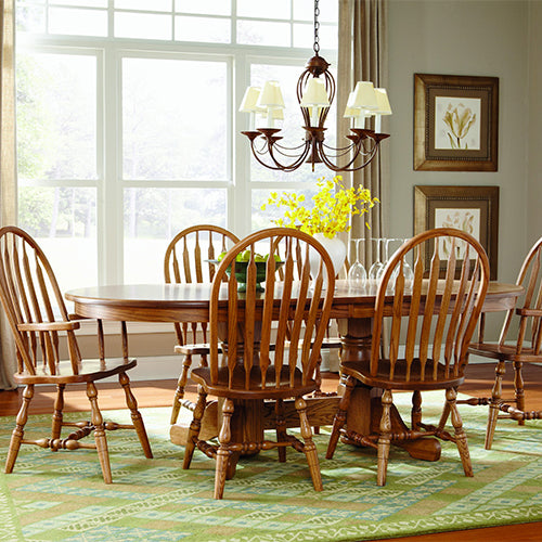 Traditional dining room with medium wood, oval dining table surrounded by matching Windsor style dining chairs.