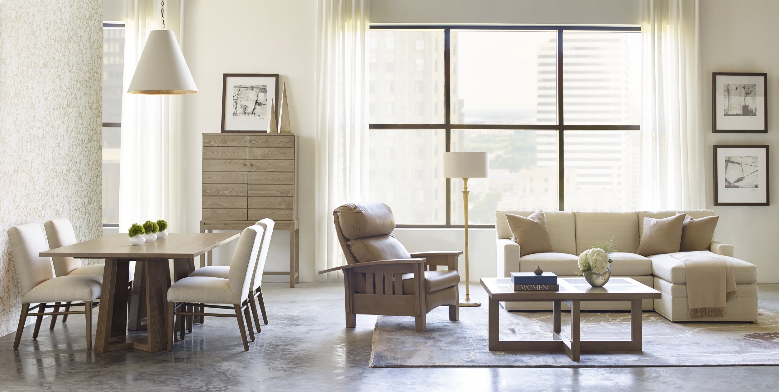 Living room scene from Stickley featuring a beige sofa, taupe leather and wood recliner, and a dining area.
