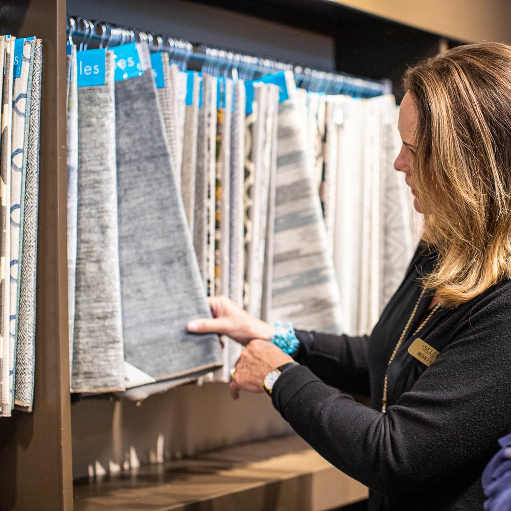 An interior designer looking at fabric samples hanging on a wall.