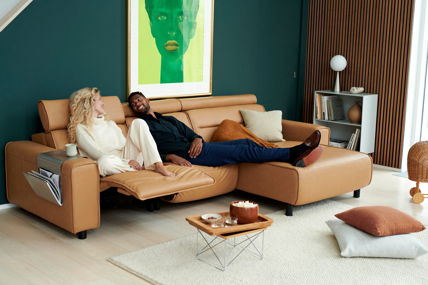 Two people sitting on a tan leather reclining sofa
