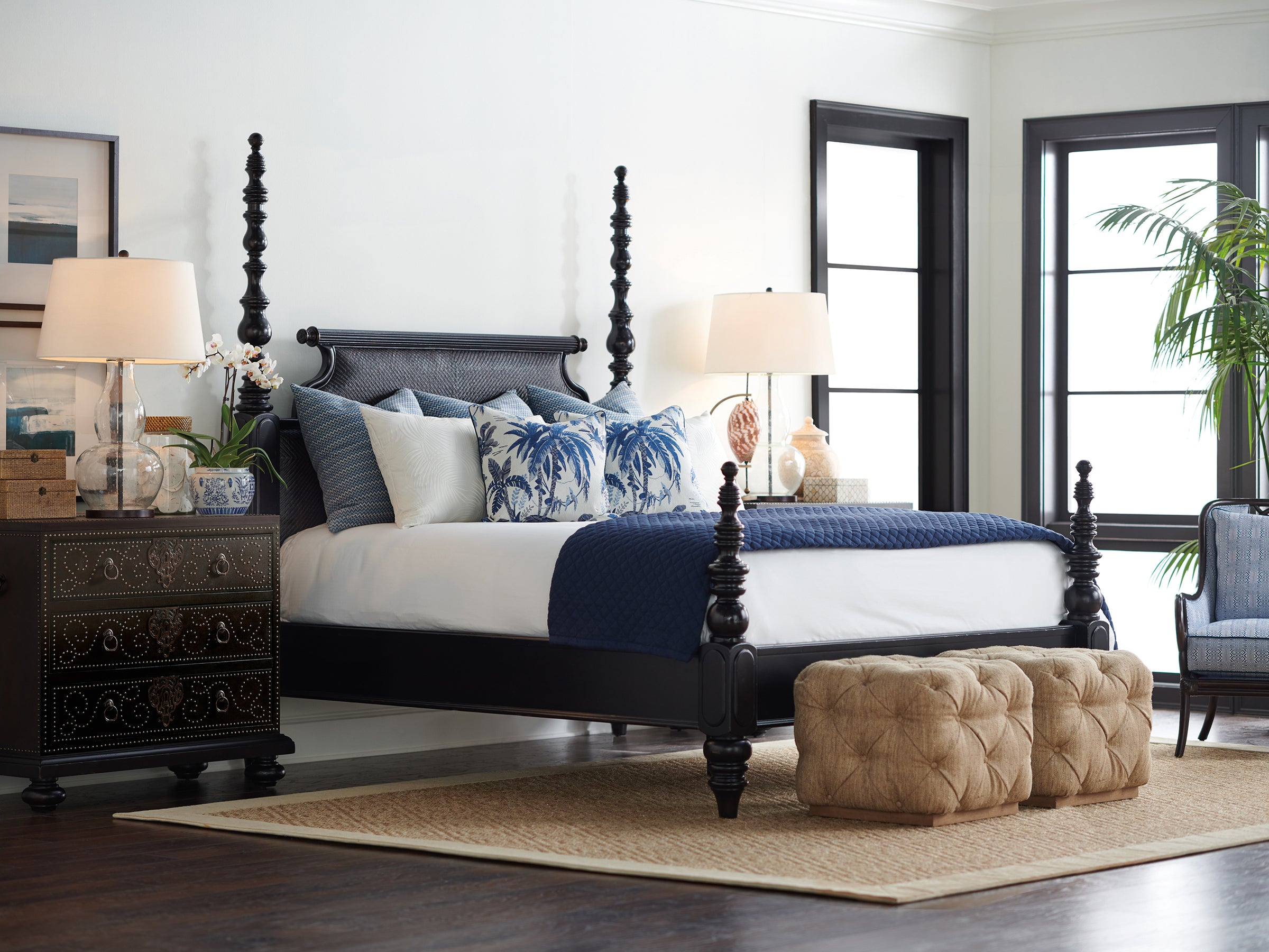 A traditional bedroom scene from Tommy Bahama Home's Kingstown collection featuring a dark wood poster bed and matching nightstand.