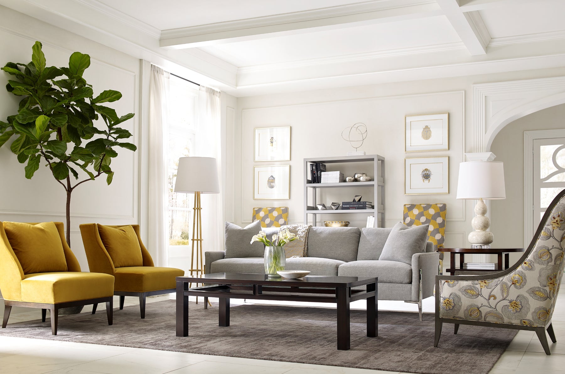Living room scene with a gray sofa, two yellow chairs, a coffee table, and a patterned fabric chair.