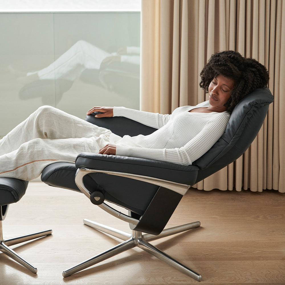 A person reclining in a black leather arm chair