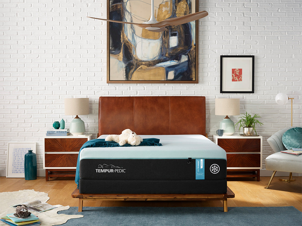 A Tempur-Pedic mattress on a leather upholstered bed frame in a casual bedroom setting.